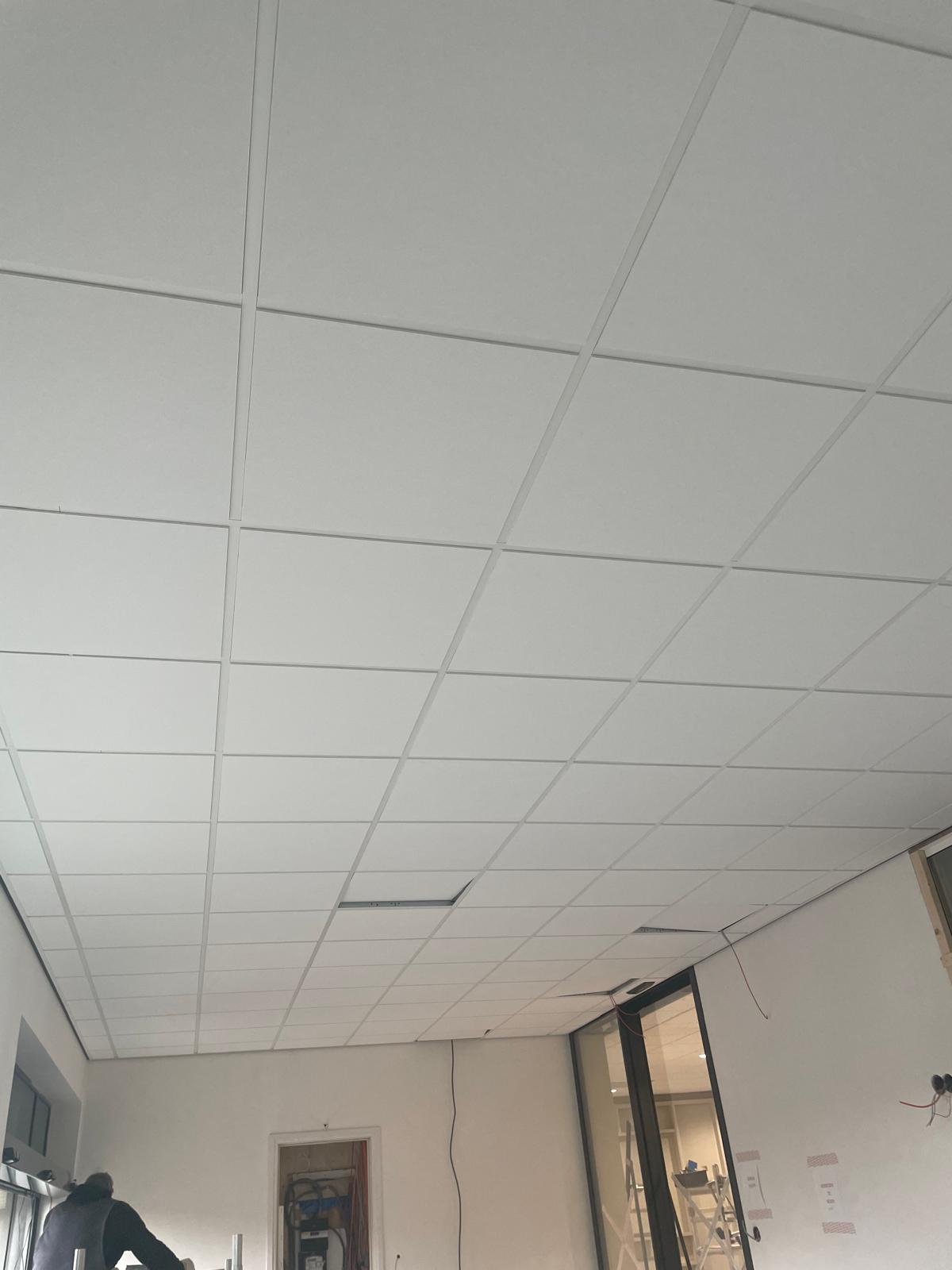 Systeemplafond tijdens de montage, met deels nog open raster en losse bekabeling